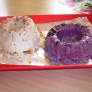 Ein weißer und ein violetter Gugelhupf aus Eiscreme liegen in einer flachen, roten Schale.