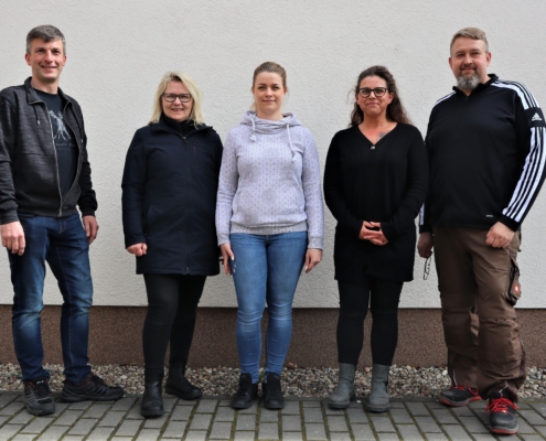 Der neu gewählte Betriebsrat hat sich zum Gruppenfoto vor einer helle Wand der Werkstatt aufgestellt. Von links nach rechts sind das: Thomas Hensel, Christiane Engel, Janine Schurkus, Jeanette Schütze und Thomas Hesse.. Alle lächeln.